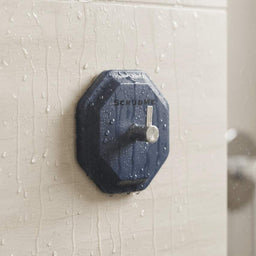 ScrubMe HookMe Breathtaking Blue adhesive wall hook in a wet shower fixed to beige bathroom tiles with water droplets running down the surface.