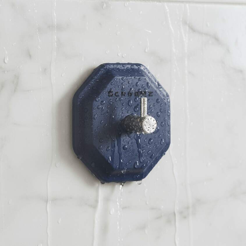 ScrubMe HookMe Breathtaking Blue adhesive hook mounted on a white marble bathroom wall with water droplets on the tiles.