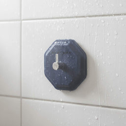 ScrubMe HookMe Breathtaking Blue adhesive wall hook attached to white bathroom tiles in a modern shower.