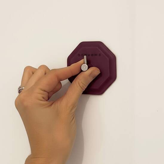 Hand Installing ScrubMe HookMe Passionate Purple hook onto a smooth white wall