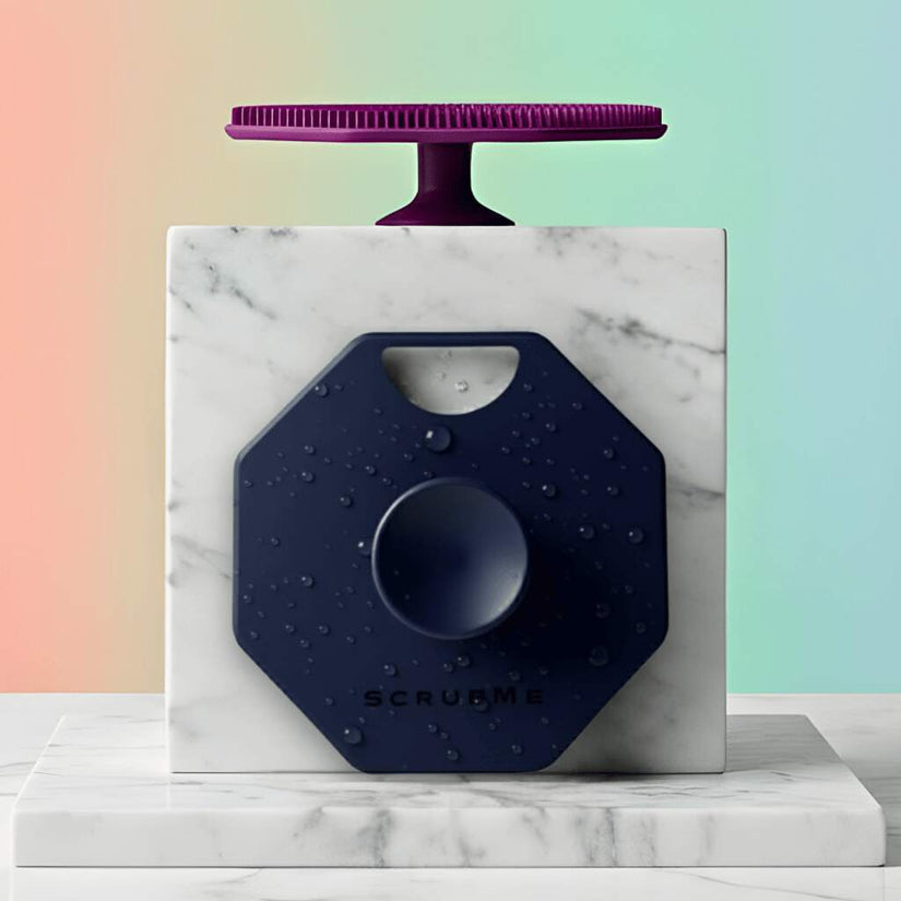 Hero Image ScrubMeBody Breathtaking Blue and Passionate Purple silicone body scrubbers styled on marble blocks against a pastel gradient background.