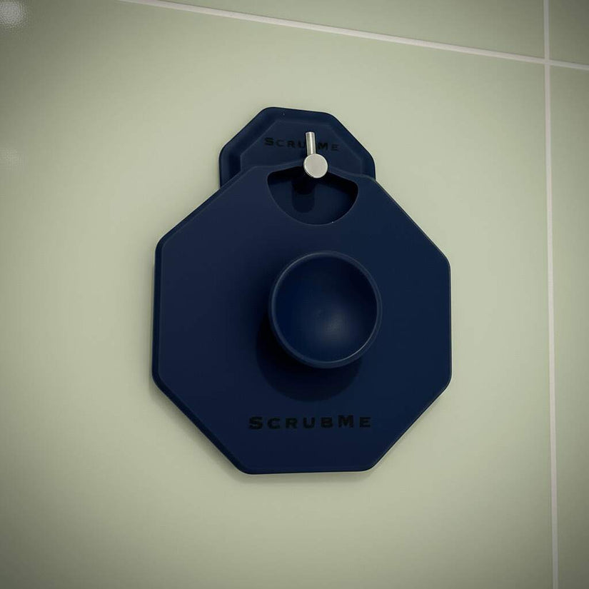 ScrubMeBody Breathtaking Blue body scrubber hanging on a chrome hook against soft green bathroom tiles for easy drying and storage.