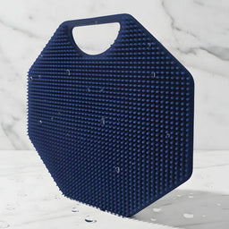 Hero image of the ScrubMeBody Breathtaking Blue body scrubber standing on a marble surface, highlighting thousands of fine silicone bristles with water droplets.