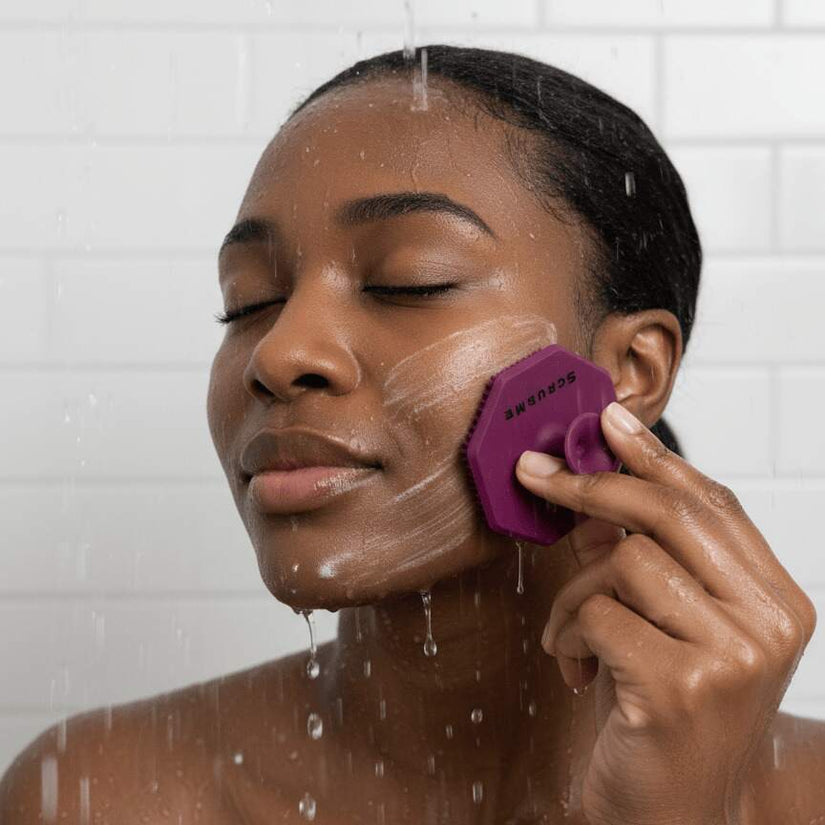 Woman gently cleansing her face in the shower with the ScrubMeFace Passionate Purple silicone exfoliating face scrubber.