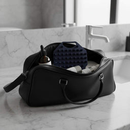 ScrubMeScalp Breathtaking Blue scalp scrubber in a black travel was bag with hair and body products on a
bathroom counter