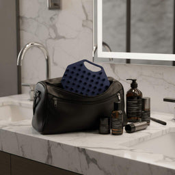ScrubMeScalp Breathtaking Blue scalp scrubber packed in a black wash bag on a marble bathroom sink with grooming products